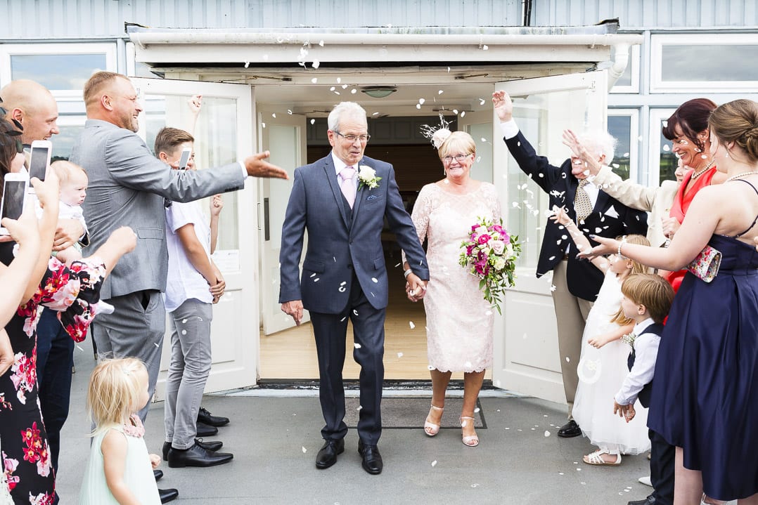 A mature couple are showered in confetti on their wedding day
