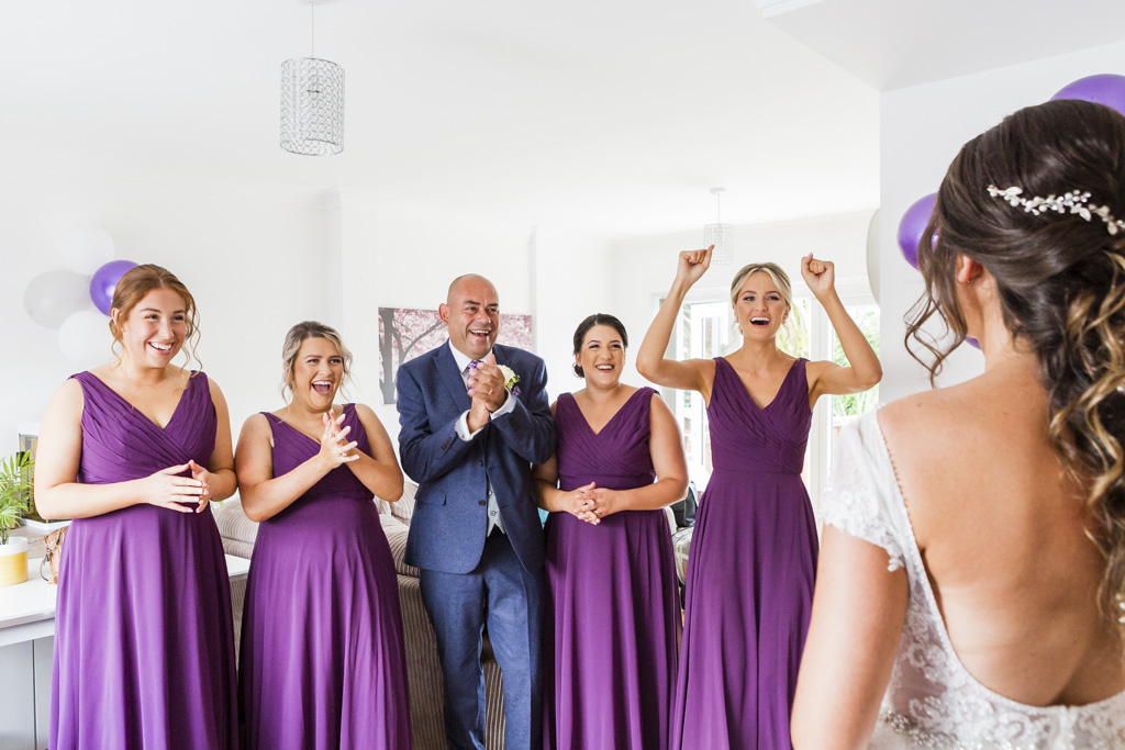 Bridesmaid and father of the bride react ot seeing the bride in her dress