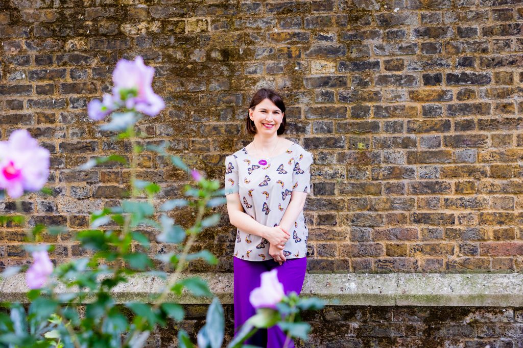 Celebrant Kathryns in purple against a brick wall
