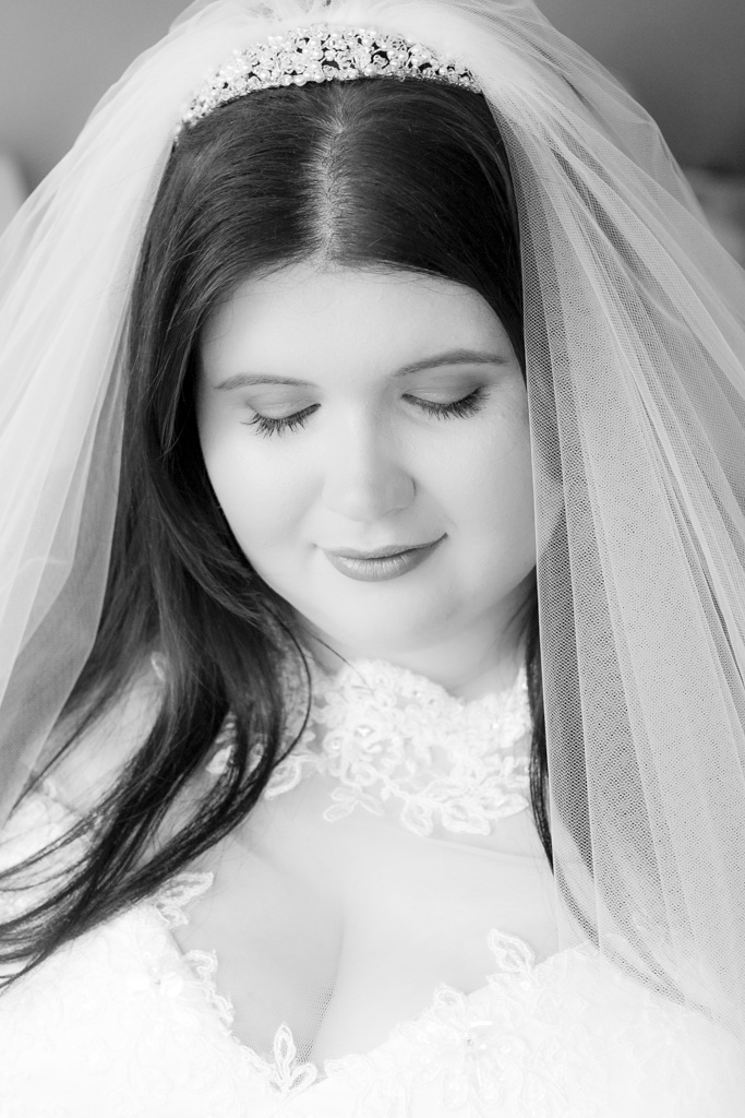 A black and white headshot of a bride looking down