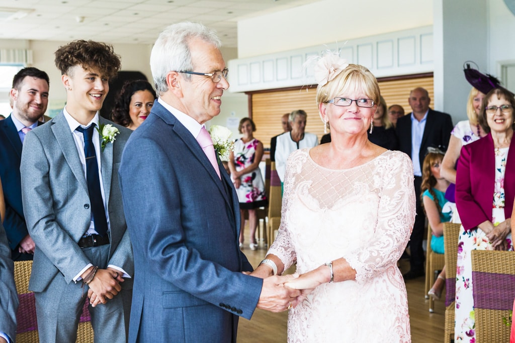 A couple hold hands during their Essex wedding ceremony