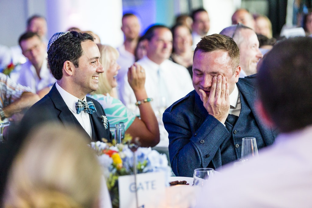 Two grooms laughing during the speeches at Kings Place London