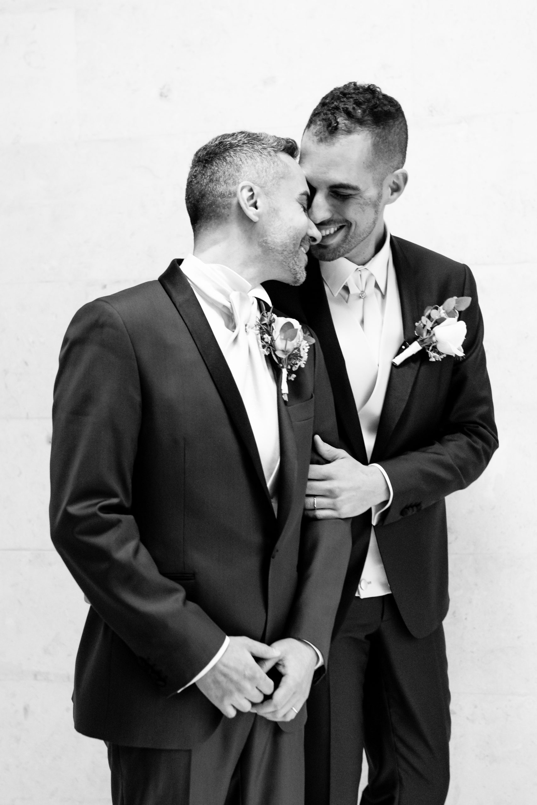 A black and white image of two grooms heads together o their London wedding day