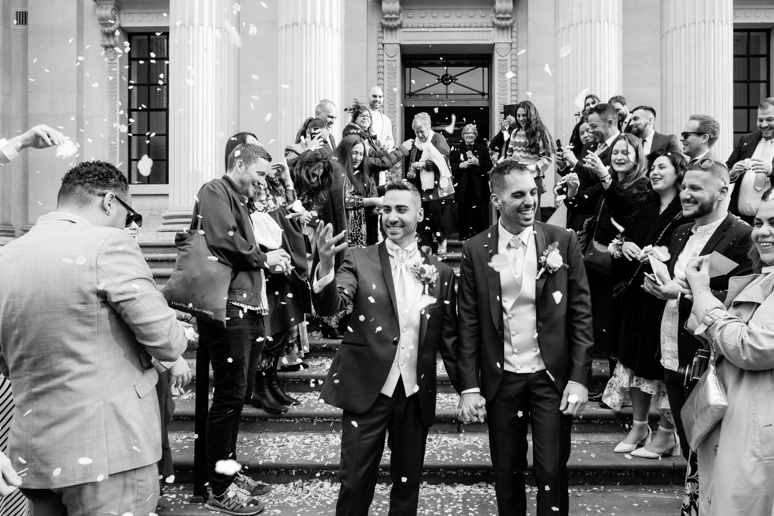 Two grooms covered in confetti outside Marylebone Town Hall in London 