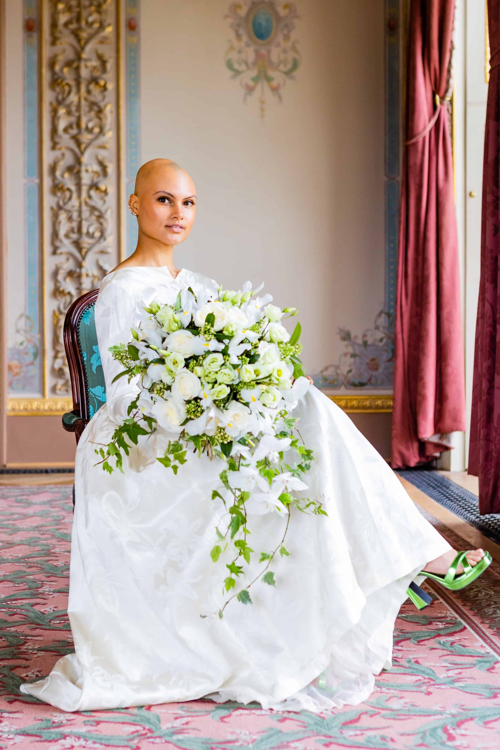 A bride at Hylands House in Essex, sitting with her flowers.