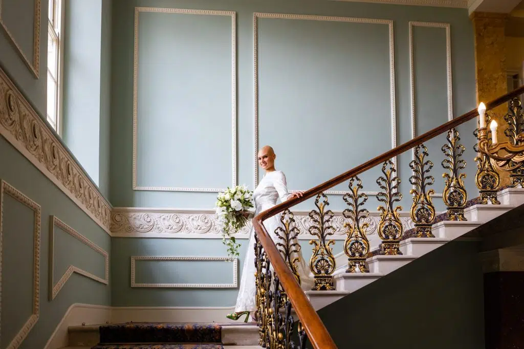 A bride walks down the stairs at Hylands House, Essex