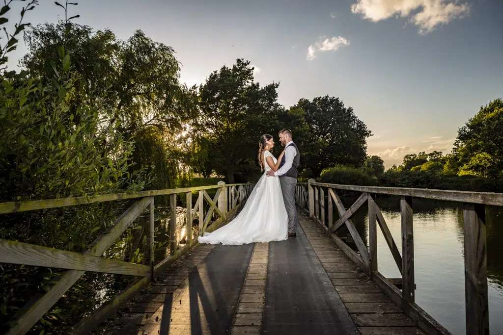 Wide shot of a bride and groom staring into each other's eyes on a bridge at their Essex wedding venue