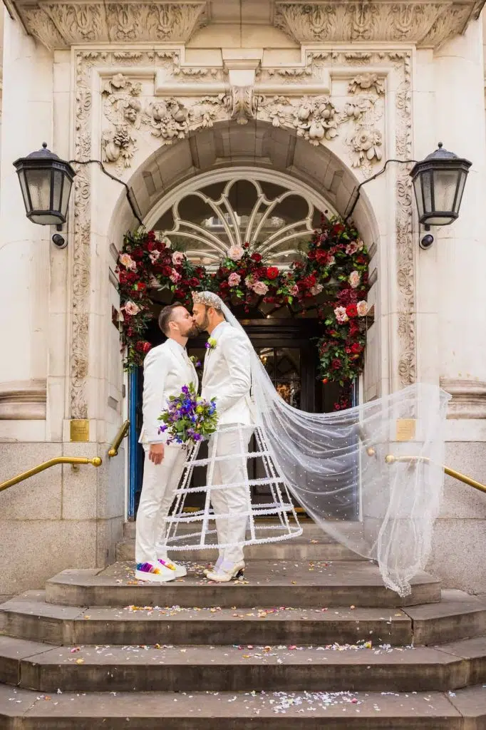 Two grooms kissing on the steps of Chelsea Old Town Hall