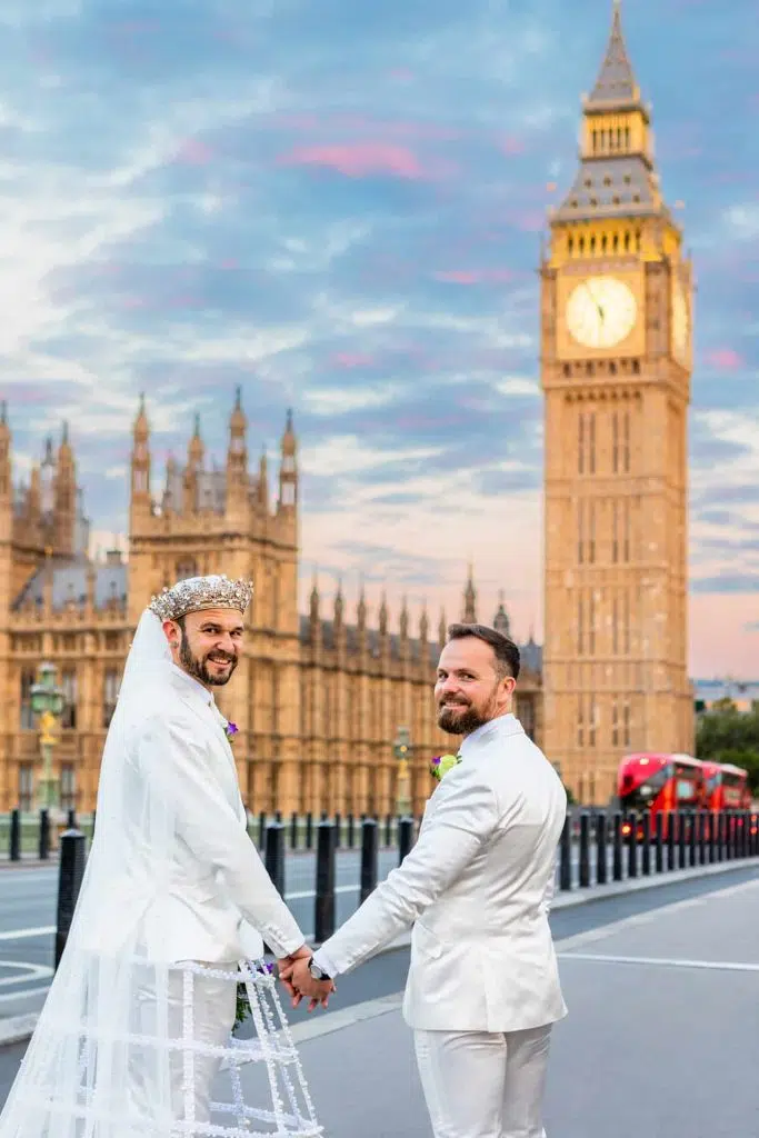 Two grooms holding hands under dramatic skies in westminster