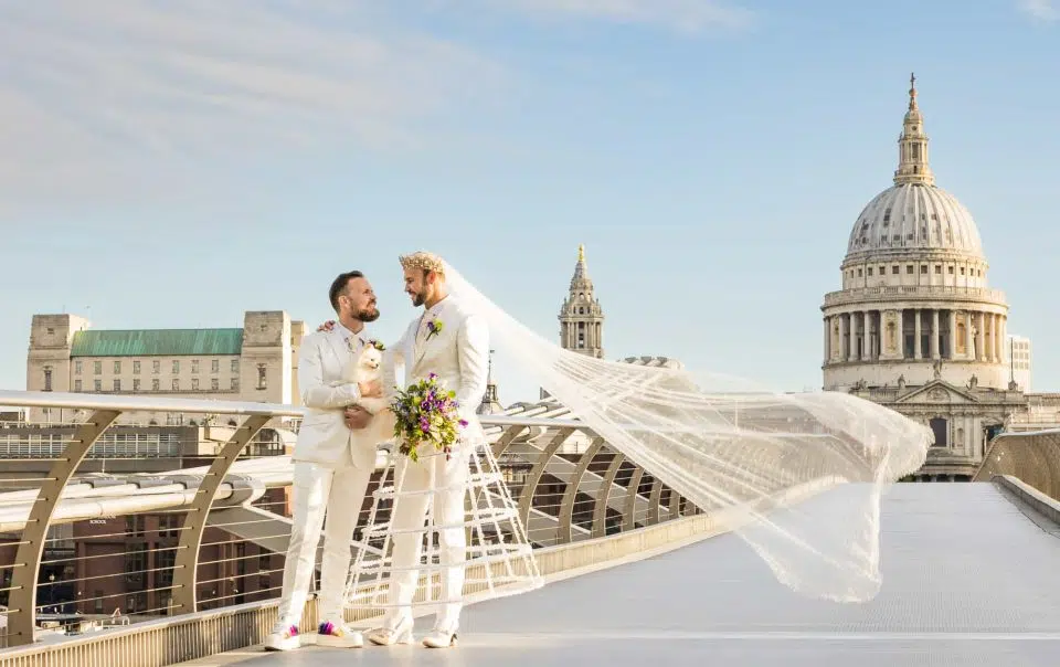 Two grooms in White - one with a veil in front of St Pauls Cathedral. Captured by London gas wedding photographer Ross Willsher
