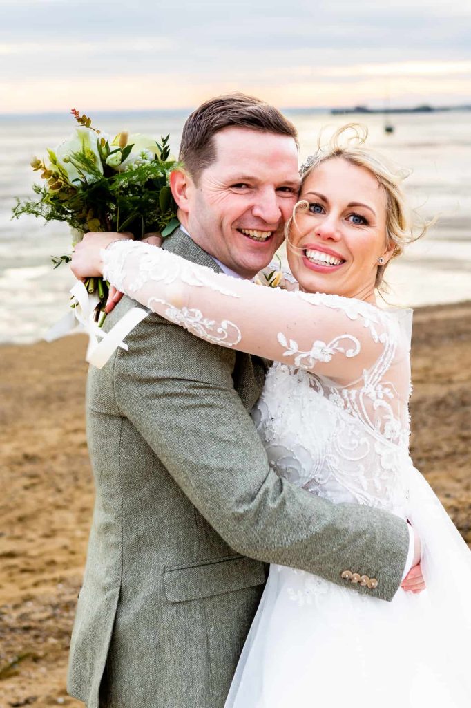 A couple pose on the beach after their Essex wedding