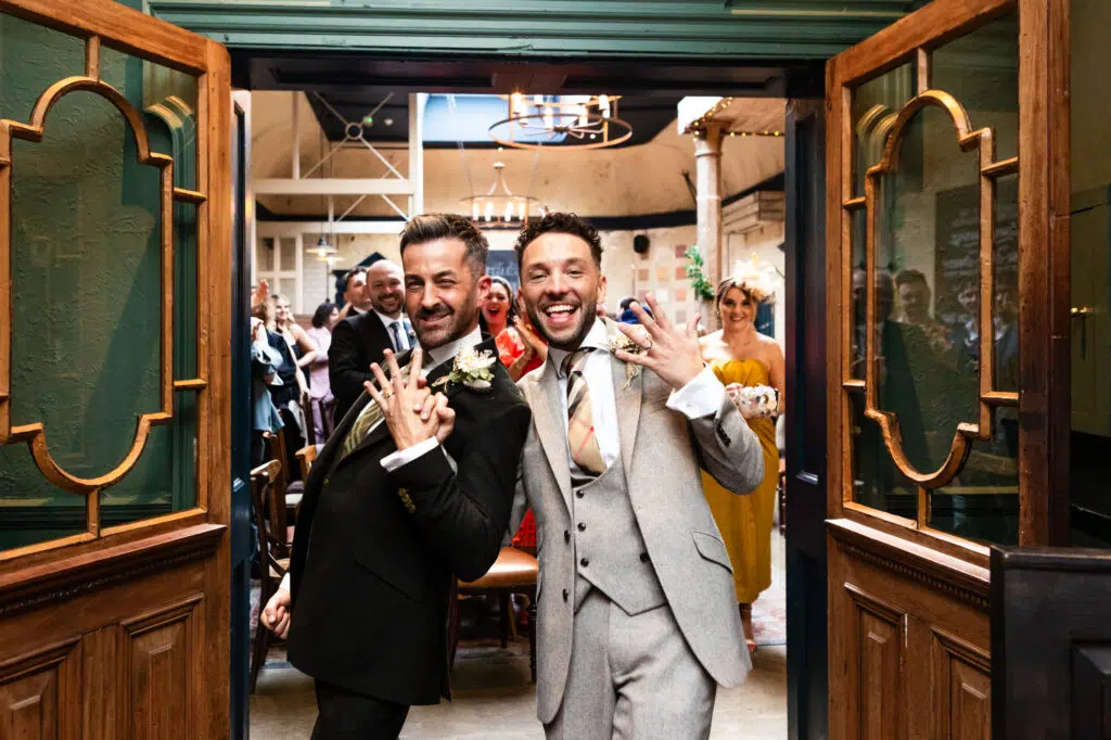Two grooms show off their wedding rings after their gay wedding ceremony.