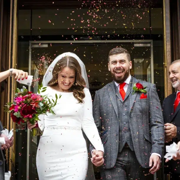 A bride and groom walking through confetti