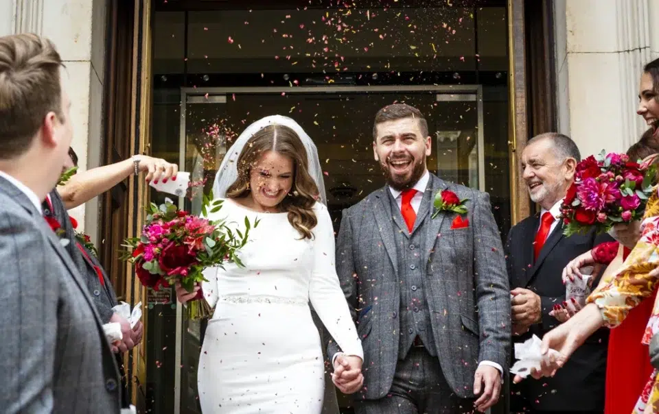 A bride and groom walking through confetti