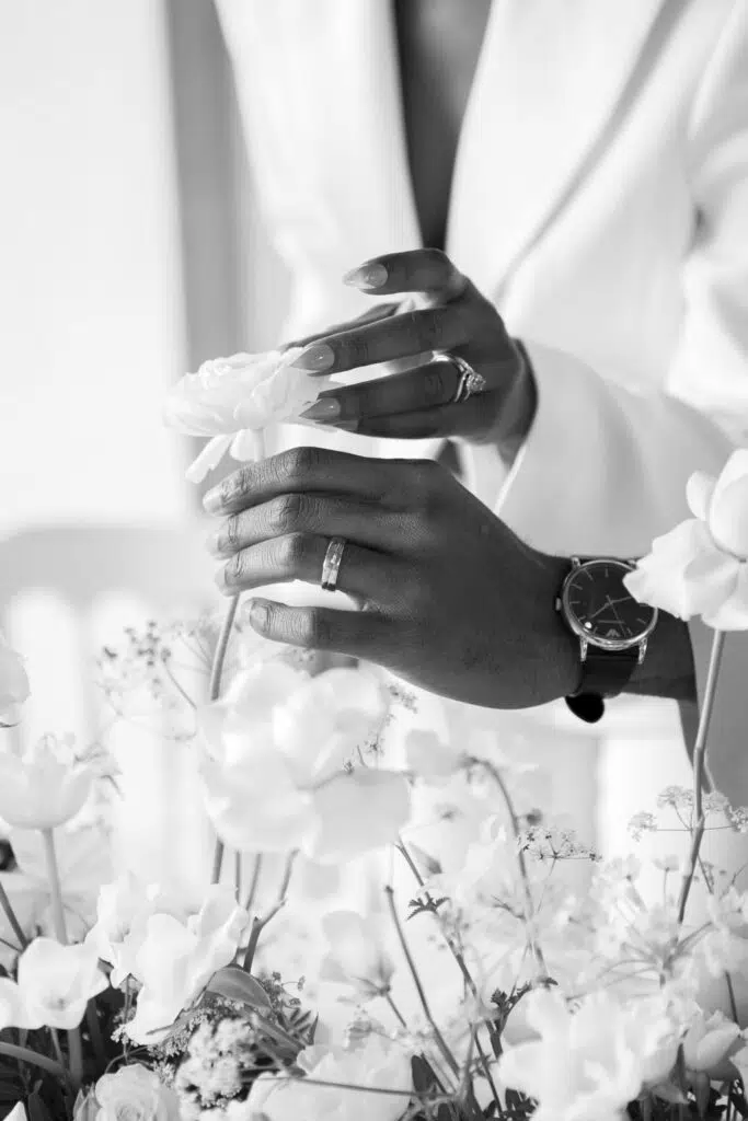 close up of couple's hands as they touch the flowers on their wedding table