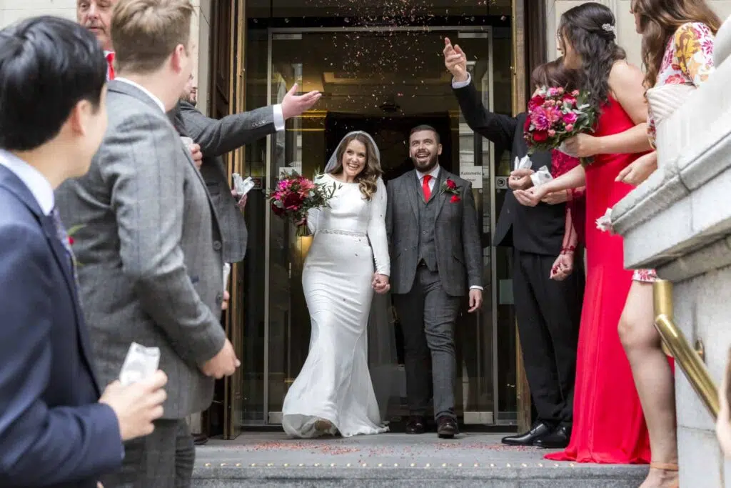 Bride and groom under confetti leaving Law Society o their wedding day