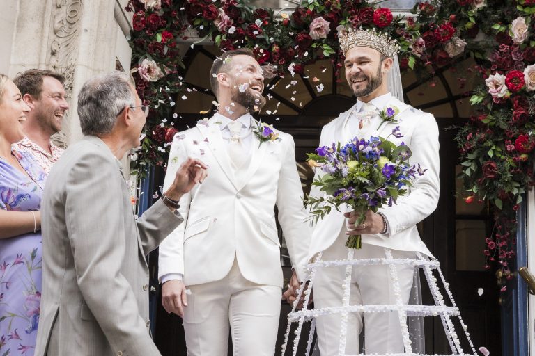 Family and friends throwing confetti over Pete and Will on the steps of Chelsea Old Town Hall after their intimate LGBTQ+ micro wedding ceremony.
