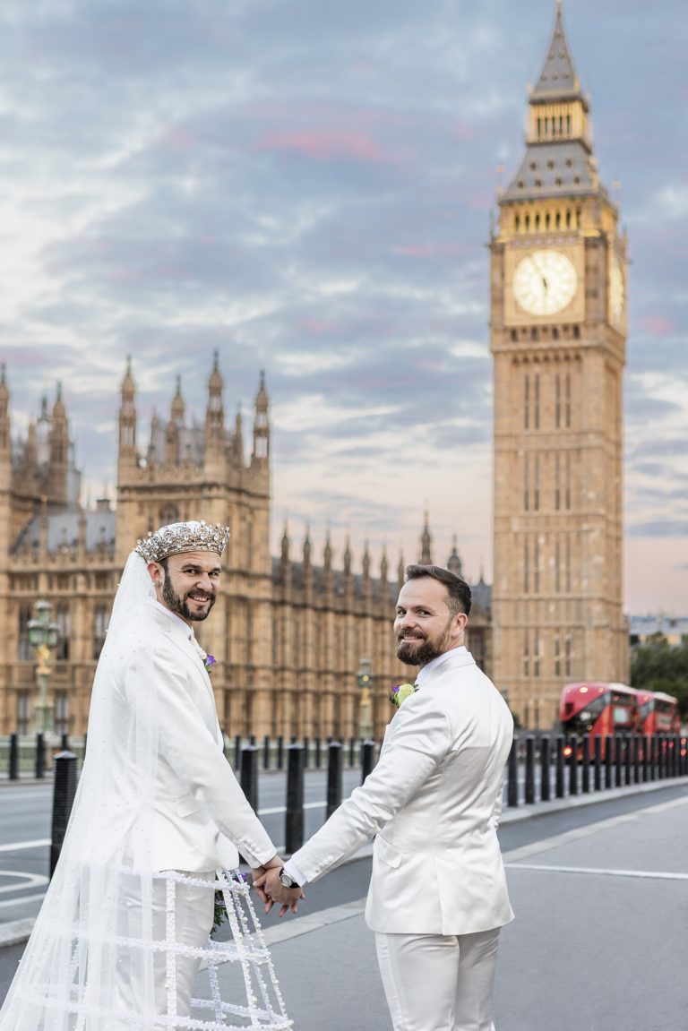 Pete and Will with their dog on Westminster Bridge at sunrise, with Big Ben glowing in the background during their LGBTQ+ London wedding portraits.